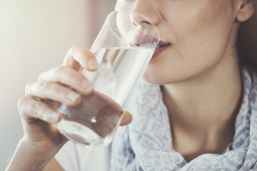hormone im trinkwasser, frau trinkt aus wasserglas