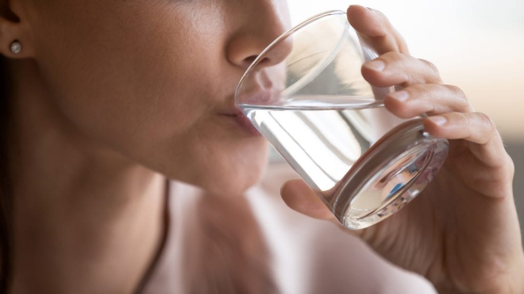 Nahaufnahme einer Frau die ein Glas hält und kalkhaltiges Wasser trinkt