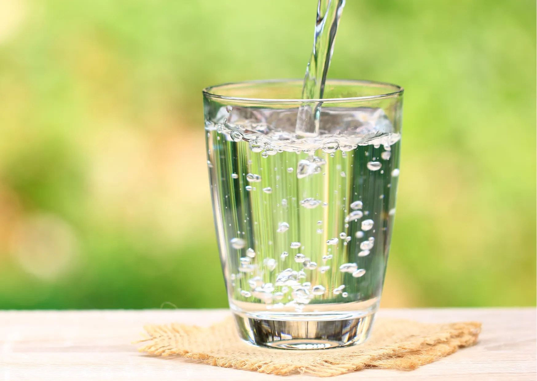 Ist kalkhaltiges Wasser ungesund? Die Fakten im Überblick Sprudelndes Wasser wird in ein Glas gegossen, im Fokus steht die Trinkwasserqualität.