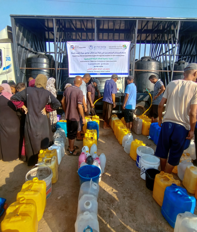 Zahlreiche Menschen in Gaza warten mit Kanistern auf dringend benötigtes Wasser von einem mobilen Versorgungspunkt.