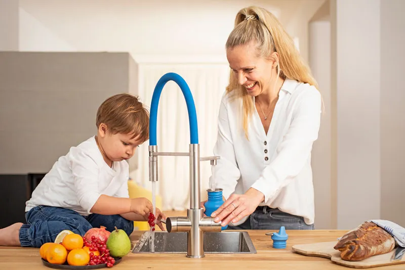 Frau und Kind nutzen einen LivingTap an einer Kücheninsel.