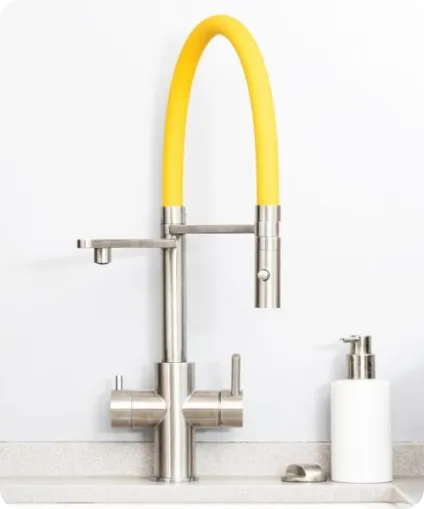 Der Living Water Wasserhahn für frisches Trinkwasser Moderner Wasserhahn mit gelbem Auslauf und zwei Hebeln auf weißer Spüle.