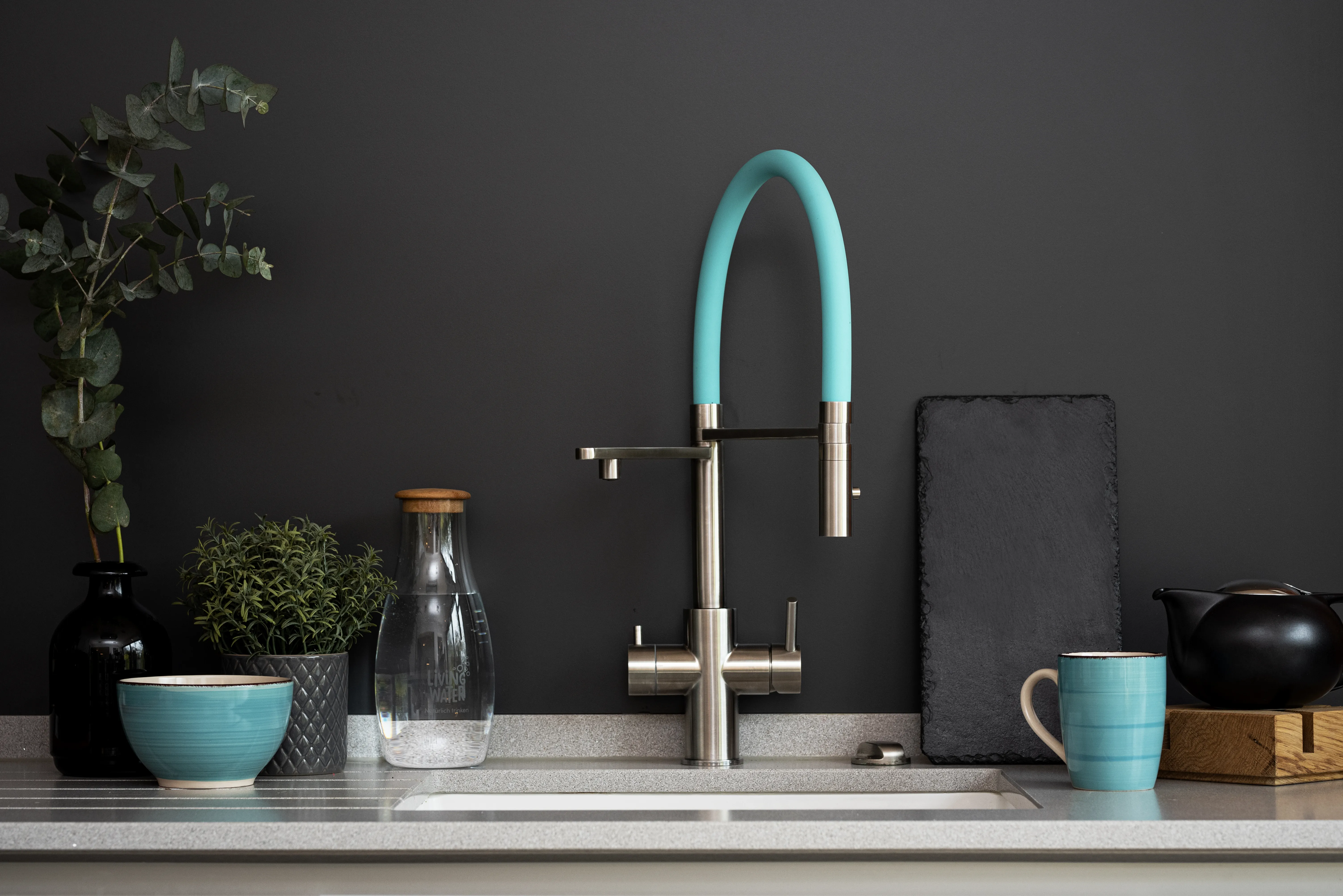 Moderne LivingTap Pro Edelstahl-Armatur mit türkisfarbener Flexbrause in einer stilvollen Designküche.
