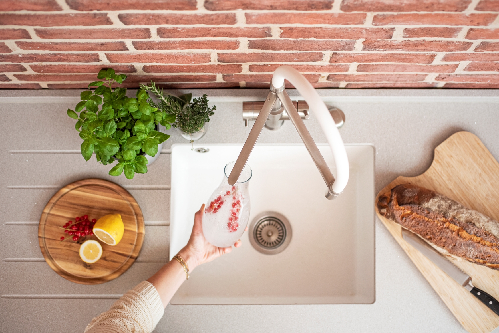 Frisches Sprudelwasser aus der Küchenarmatur Küchenarmatur mit Sprudelfunktion, Person füllt Glas mit Sodawasser