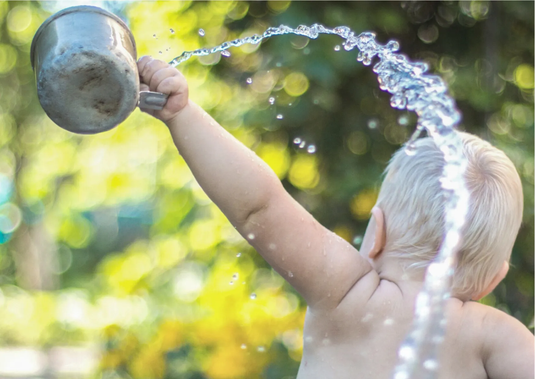 Braucht mein Baby wirklich Babywasser? Kleinkind entdeckt Wasser spielerisch – Symbolbild zum Thema Wasser für Babys.