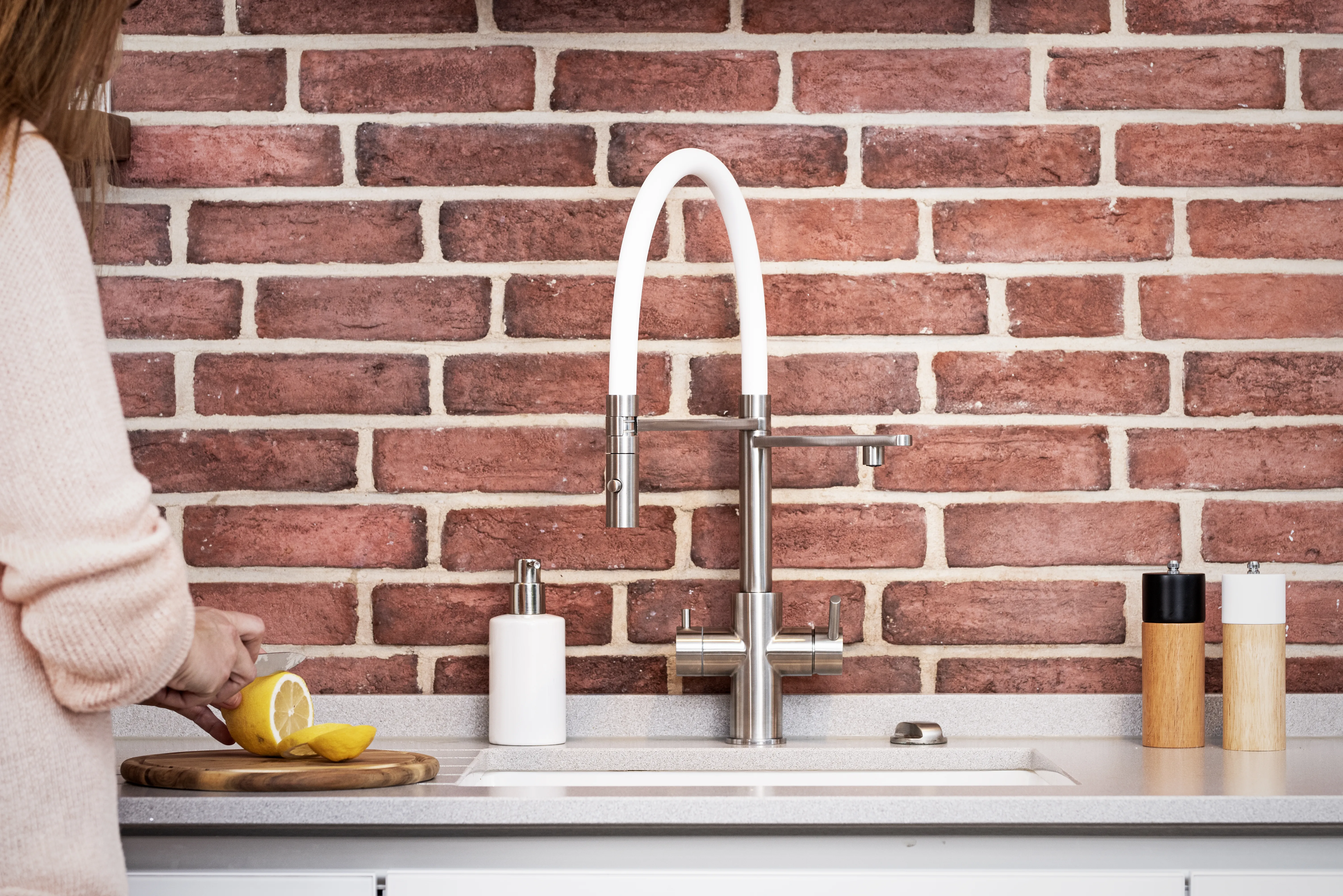 LivingTap Filterarmatur mit weißem Silikonschlauch für deine Küche Küchenarmatur mit weißem Schlauch vor Ziegelwand